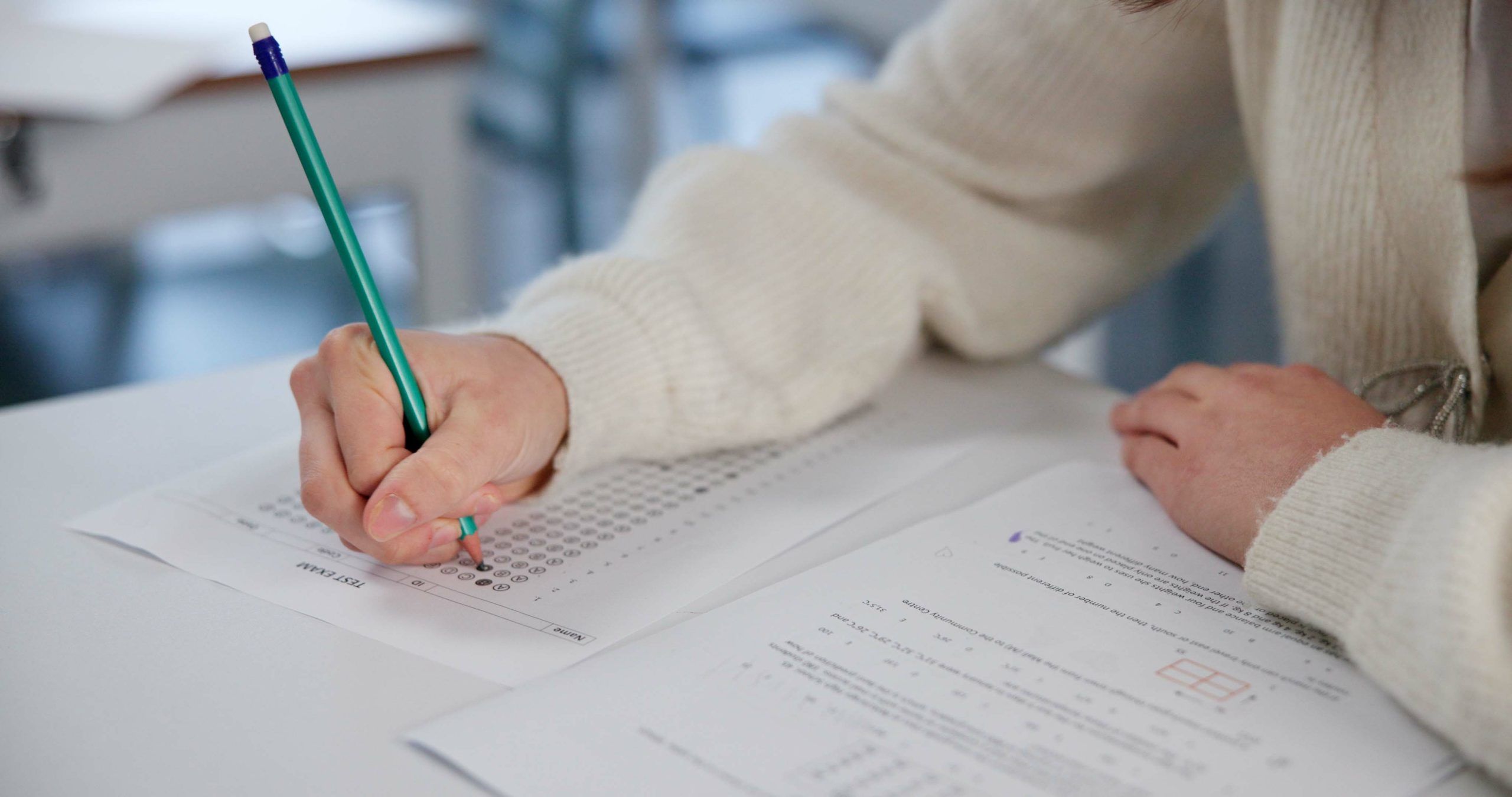 A close up of a students hand writing in an exam